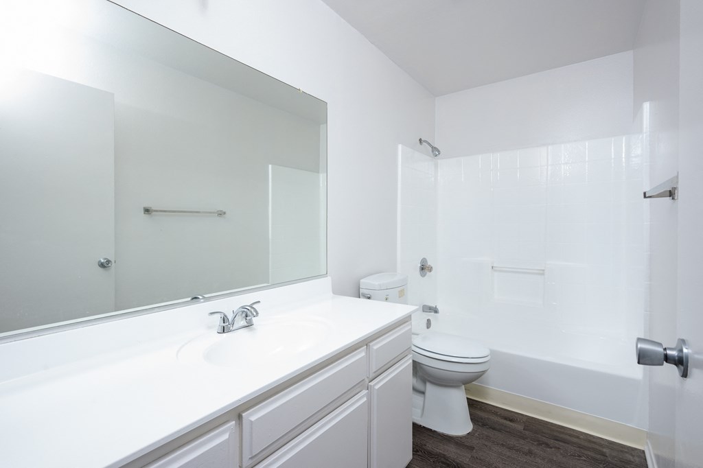 a white bathroom with a large mirror and a white toilet