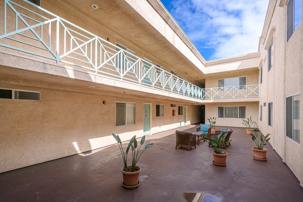 the courtyard of a building with a table and chairs and potted plants