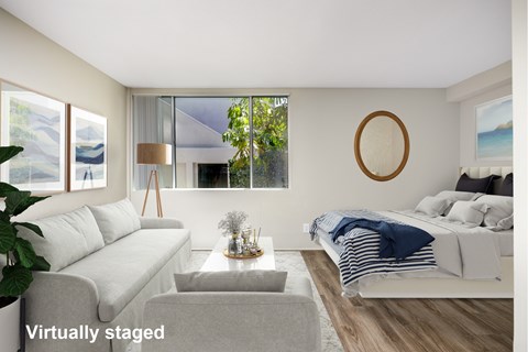 A living room with a grey couch and a white bed.