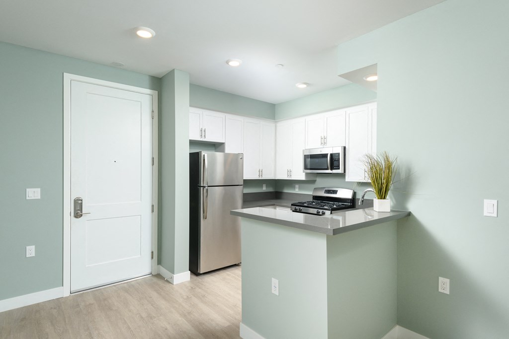 a kitchen with white cabinets and a stainless steel refrigerator