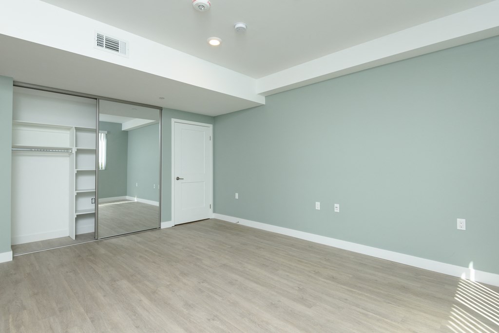 an empty living room with a sliding glass door to a closet