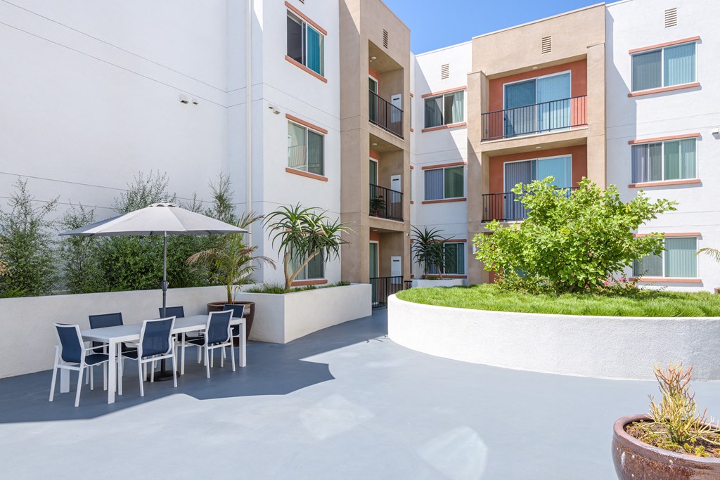 a patio with a table and chairs in front of an apartment building