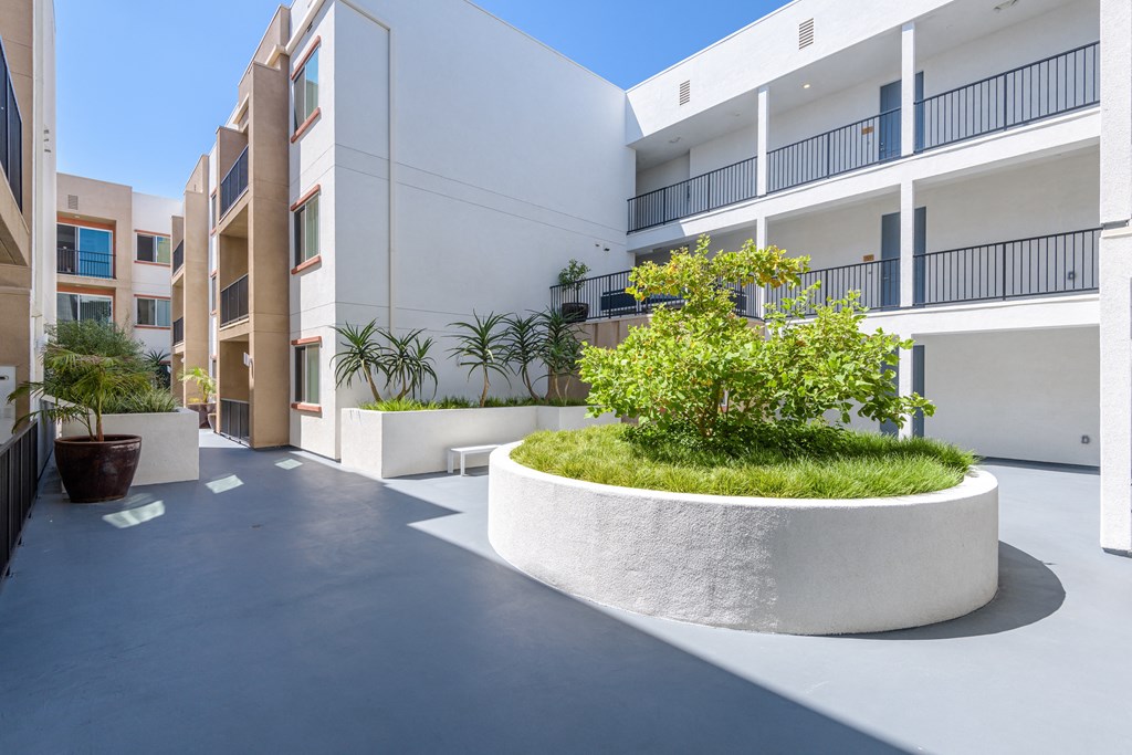 the courtyard of an apartment building with a large planter in the middle