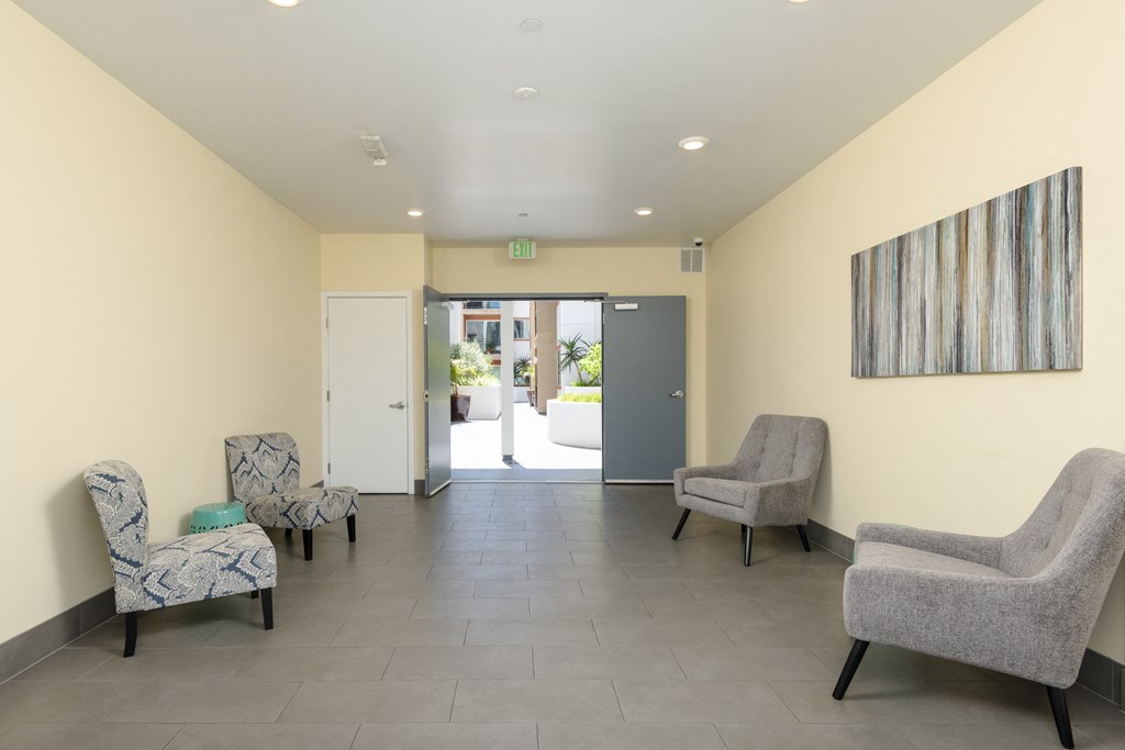 a waiting room with three chairs and a door to a lobby