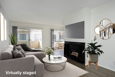 A living room with a grey couch, a black fireplace, and a television mounted on the wall.