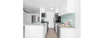 A kitchen with white cabinets and a green backsplash.