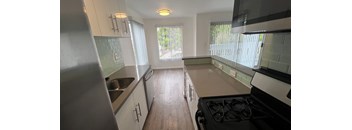 A kitchen with a stove, sink, and cabinets.