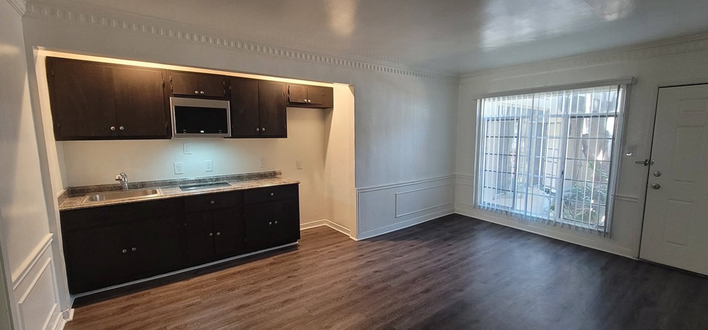 an empty living room with a kitchen and a large window