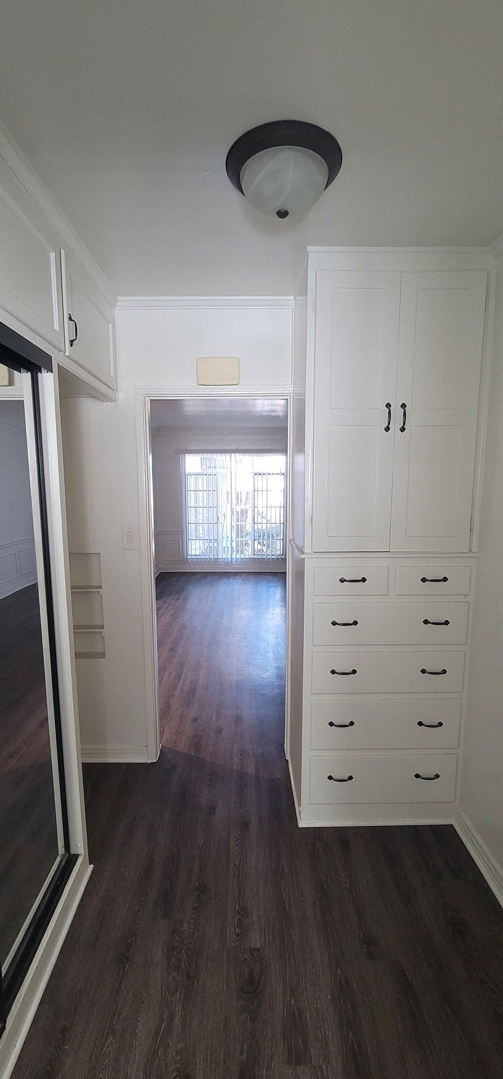 a bedroom with white cabinets and a hallway with wood floors