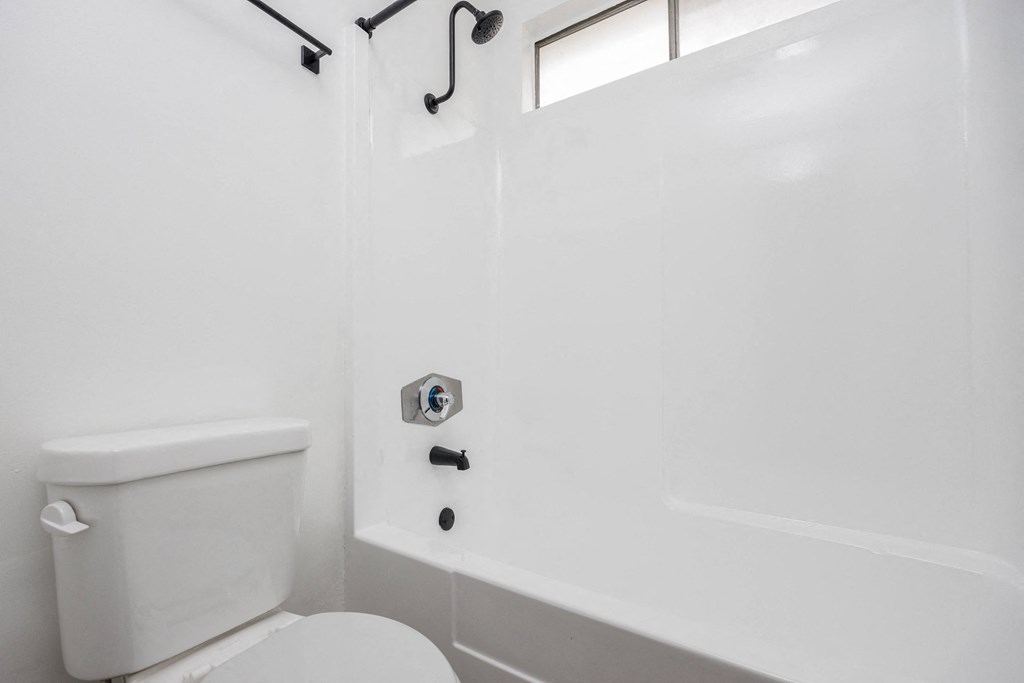 a white bathroom with a toilet and a shower