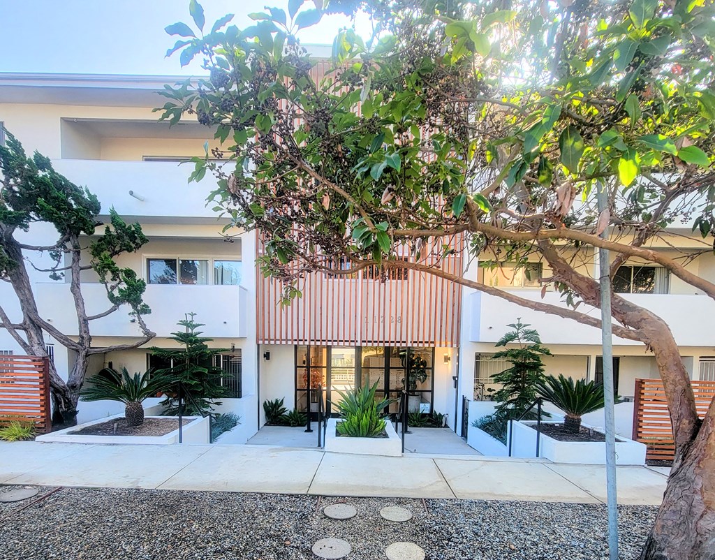 A modern house with a white exterior and a red striped awning.