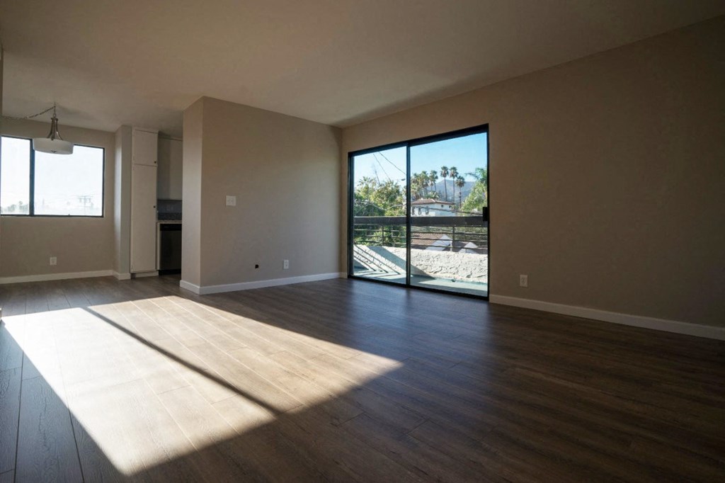 an empty living room with wood floors and a sliding glass door