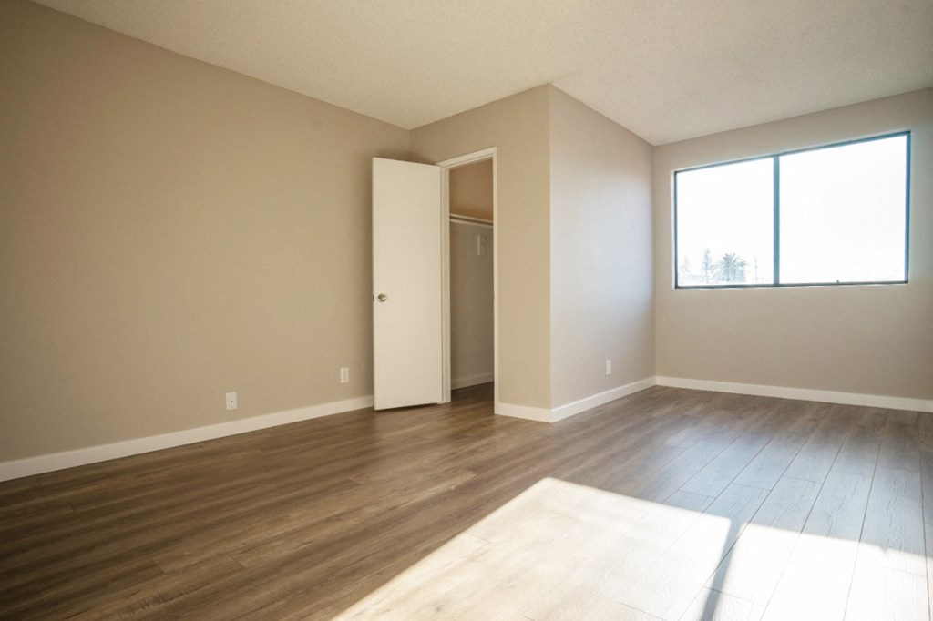 an empty living room with wood floors and a window