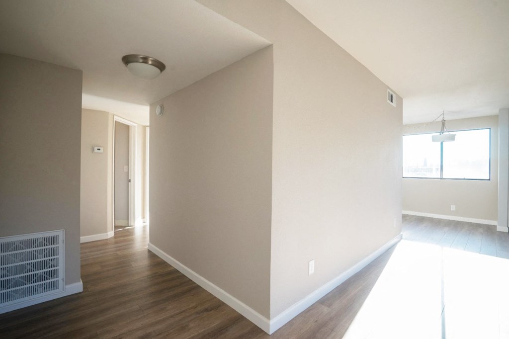 an empty living room with a wood floor and white walls