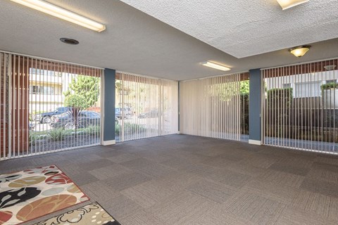 an empty living room with blinds on the windows and a rug