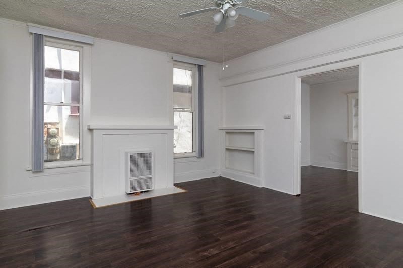 an empty living room with wood floors and a ceiling fan