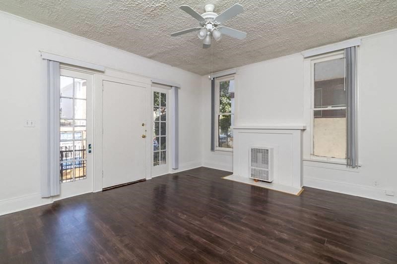 an empty living room with wood floors and a ceiling fan