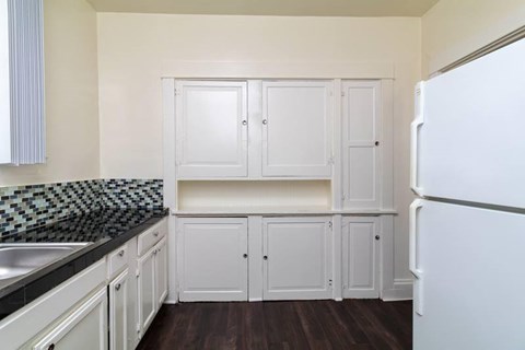 A kitchen with white cabinets and a black and white checkered backsplash.