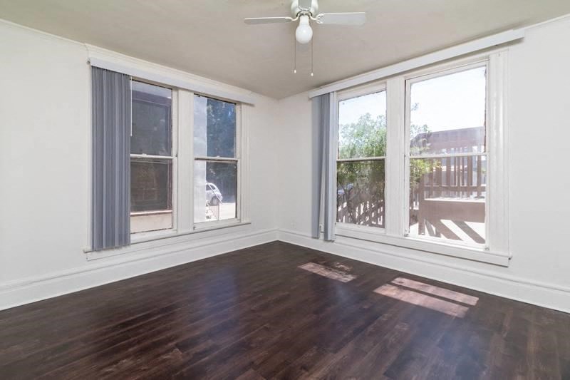 an empty living room with wood floors and a ceiling fan