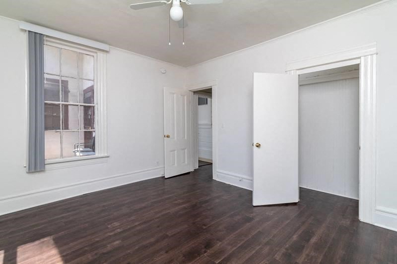an empty living room with white walls and a window and a ceiling fan