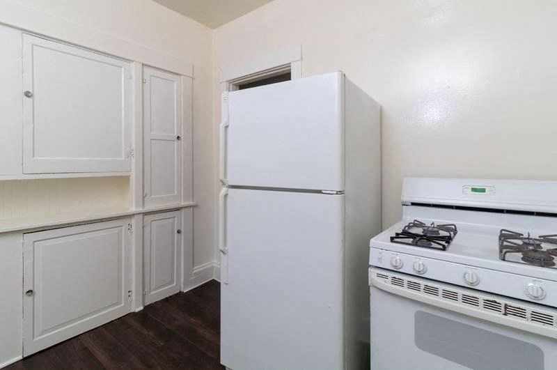 a kitchen with a stove and refrigerator and white cabinets