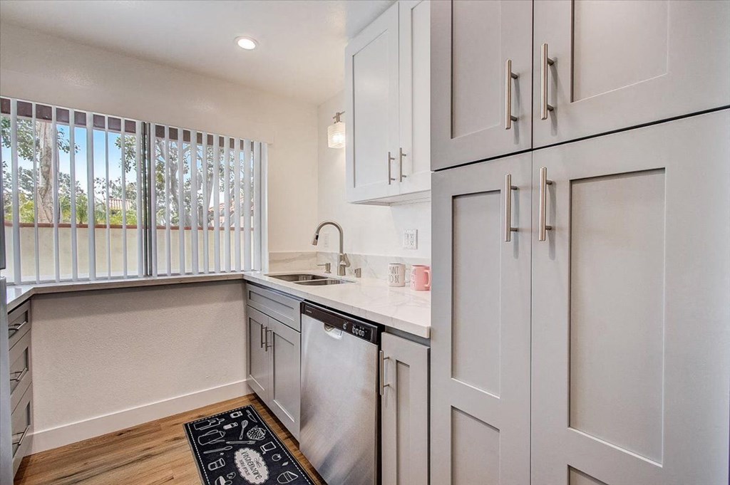 a small kitchen with white cabinets and a black and white rug