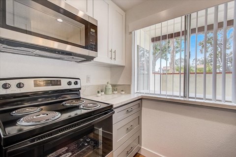 a kitchen with a stove and a microwave and a window