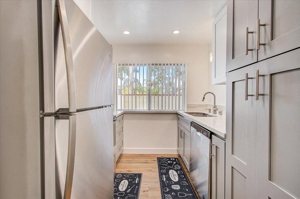 a small kitchen with white cabinets and a window