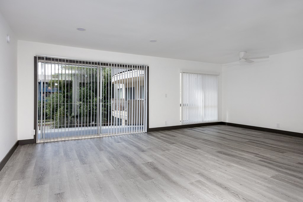 an empty living room with wood floors and a sliding glass door