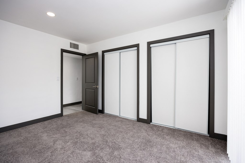 a living room with white walls and doors and a carpet
