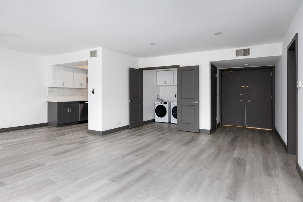 an empty living room with a washer and dryer in it and grey doors