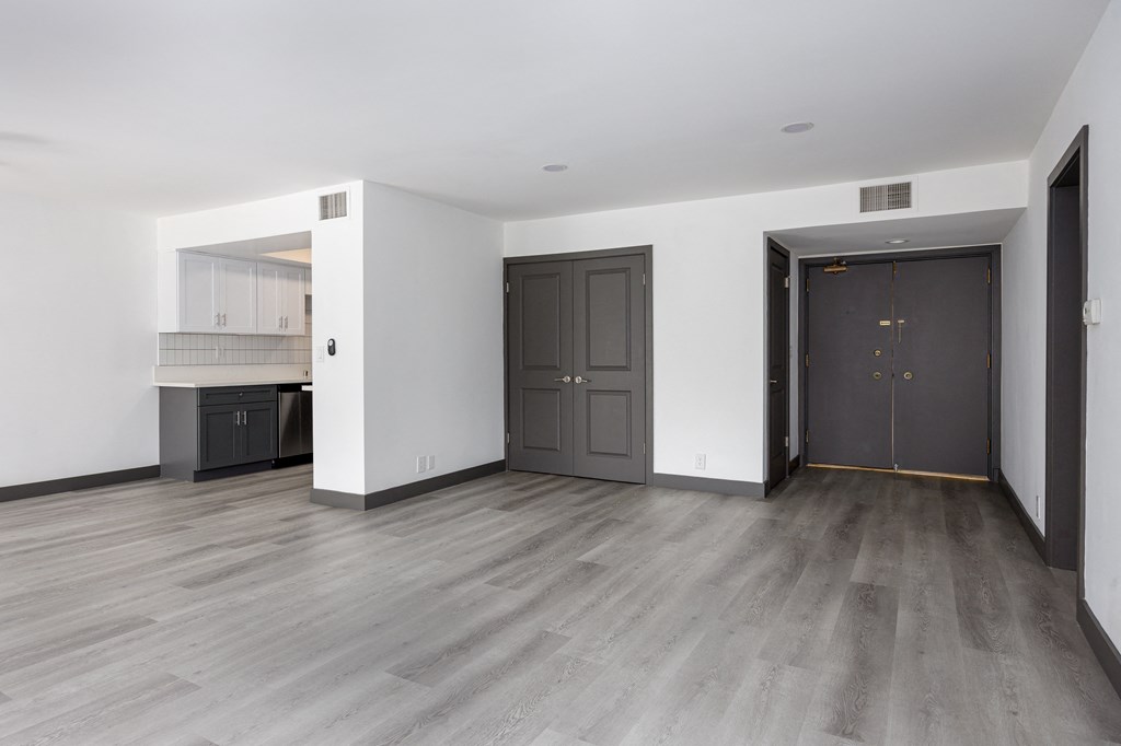 the living room and kitchen of an empty apartment with black doors and white walls