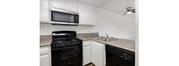 a kitchen with white cabinets and black appliances and a granite counter top