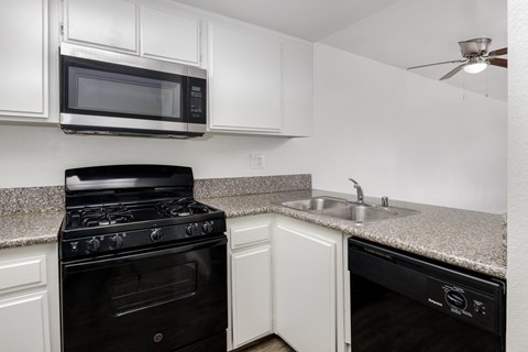 a kitchen with white cabinets and black appliances and a granite counter top