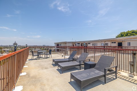 A patio with chairs and a table is overlooking a body of water.