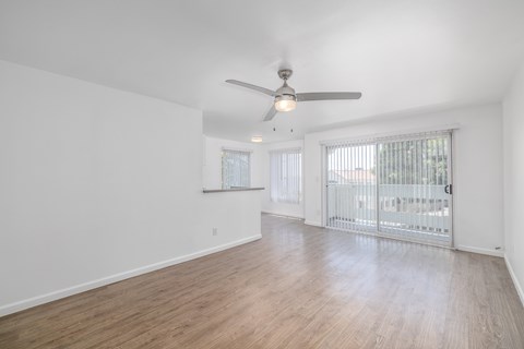 A room with a ceiling fan and sliding glass doors.
