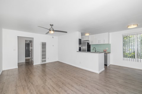 A spacious room with a ceiling fan and wooden flooring.