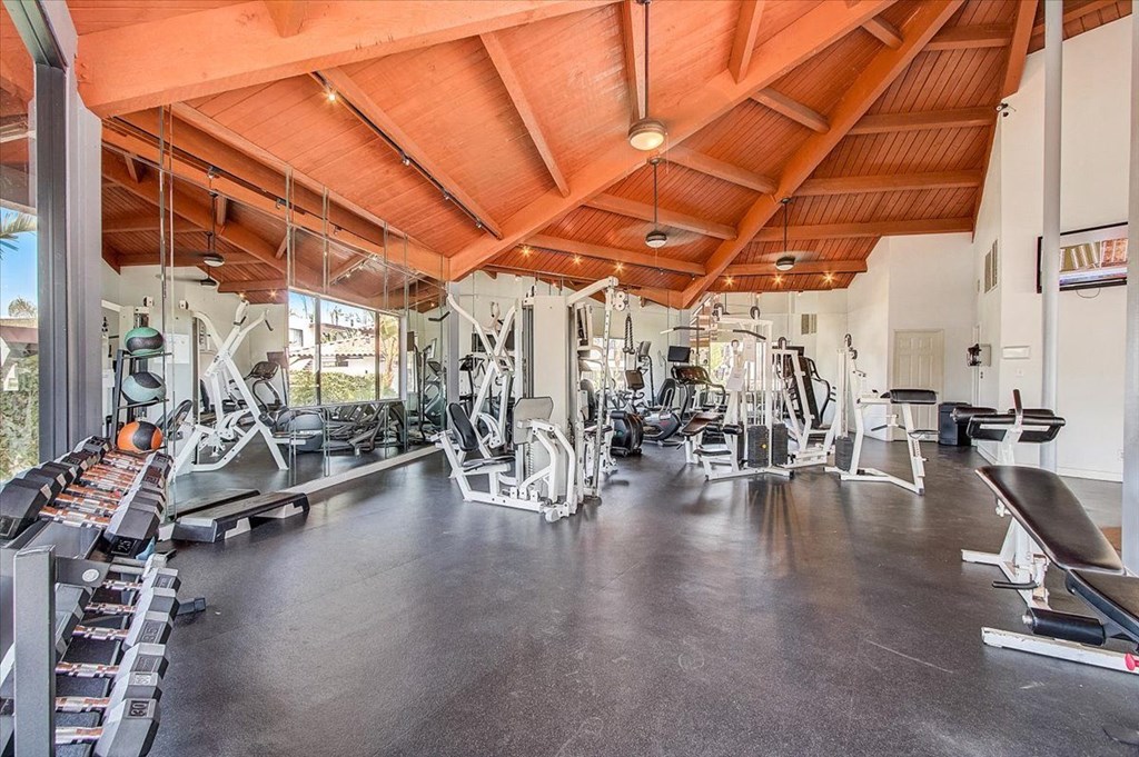 a gym with a wooden ceiling and weights on the floor