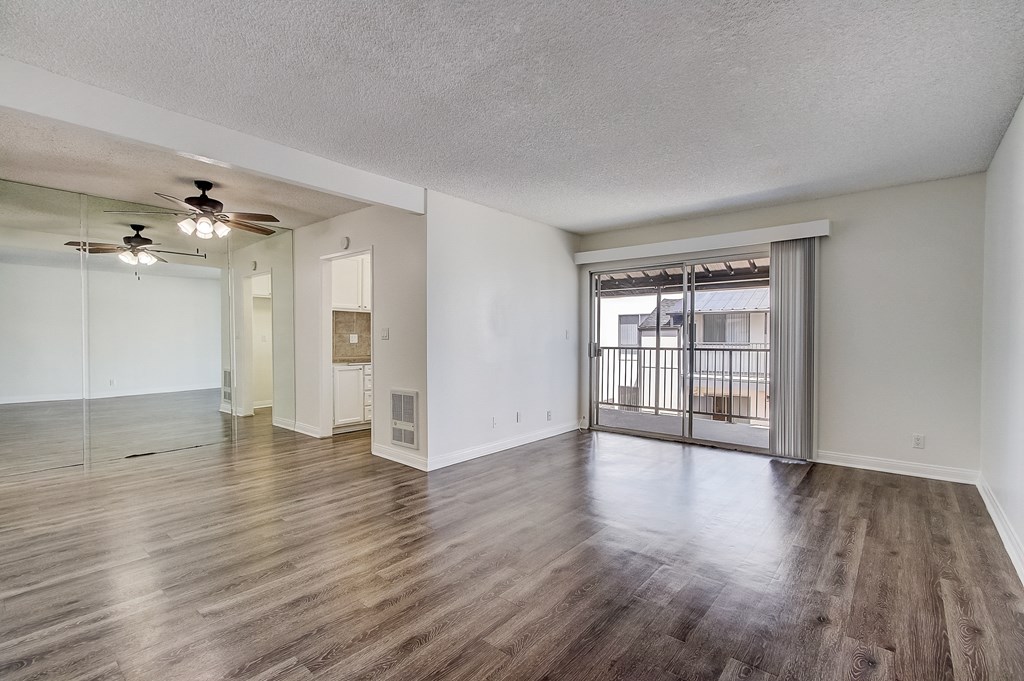 an empty living room with a sliding glass door to a balcony
