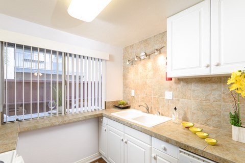a kitchen with white cabinets and a sink and a window