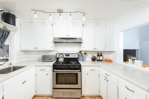 A modern kitchen with white cabinets and a stainless steel oven.