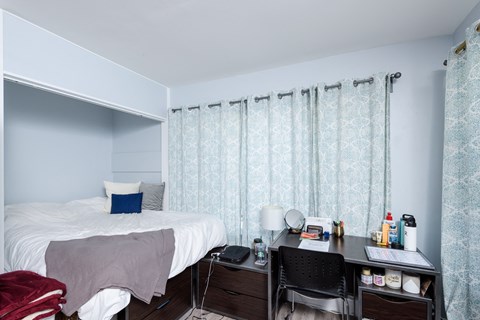 A bedroom with a bed, desk, and chair.