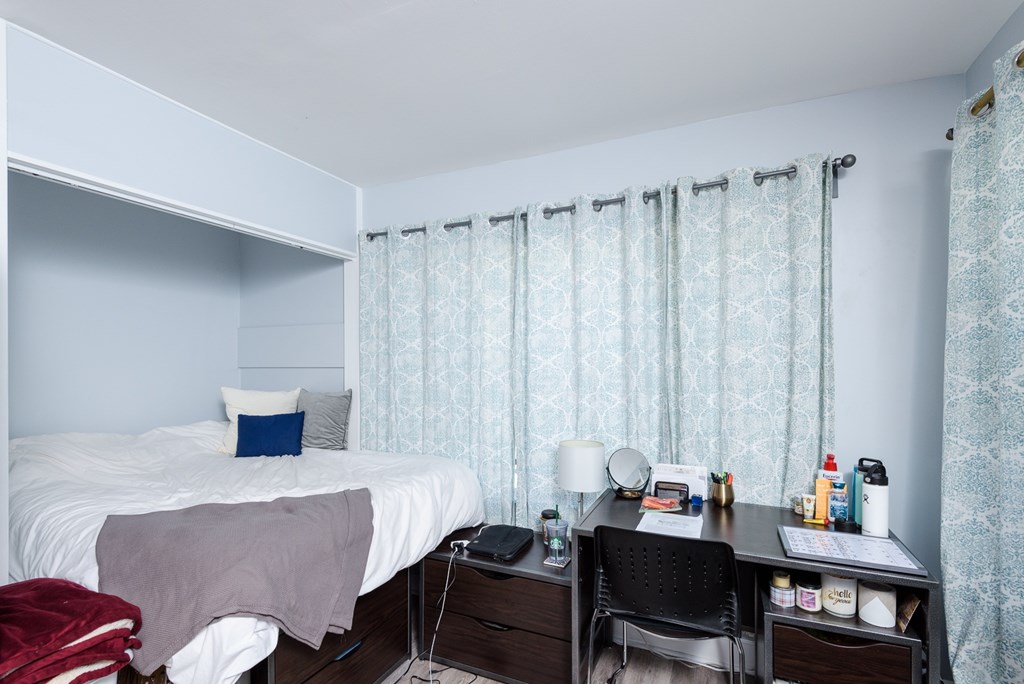 A bedroom with a bed, desk, and chair.