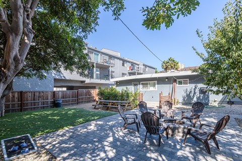 A patio with a table and chairs is surrounded by a fence and trees.