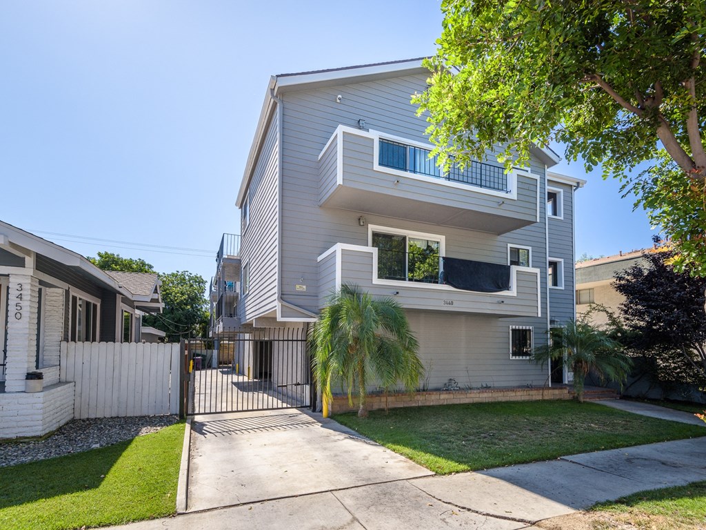 A modern two-story house with a white fence and a driveway.