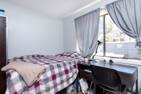 A bedroom with a bed, desk, and chair.