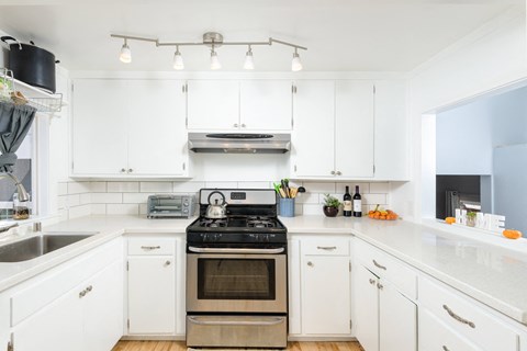 a kitchen with white cabinets and stainless steel appliances