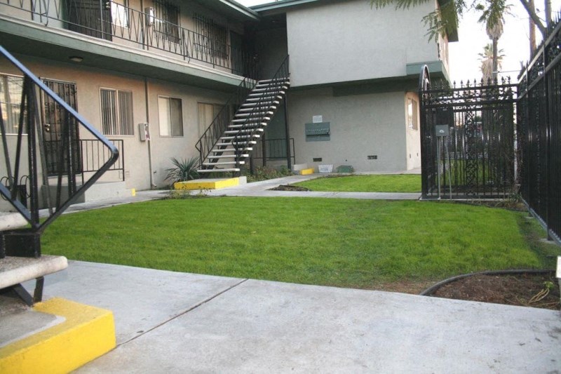 the front yard of an apartment building with a yard and stairs