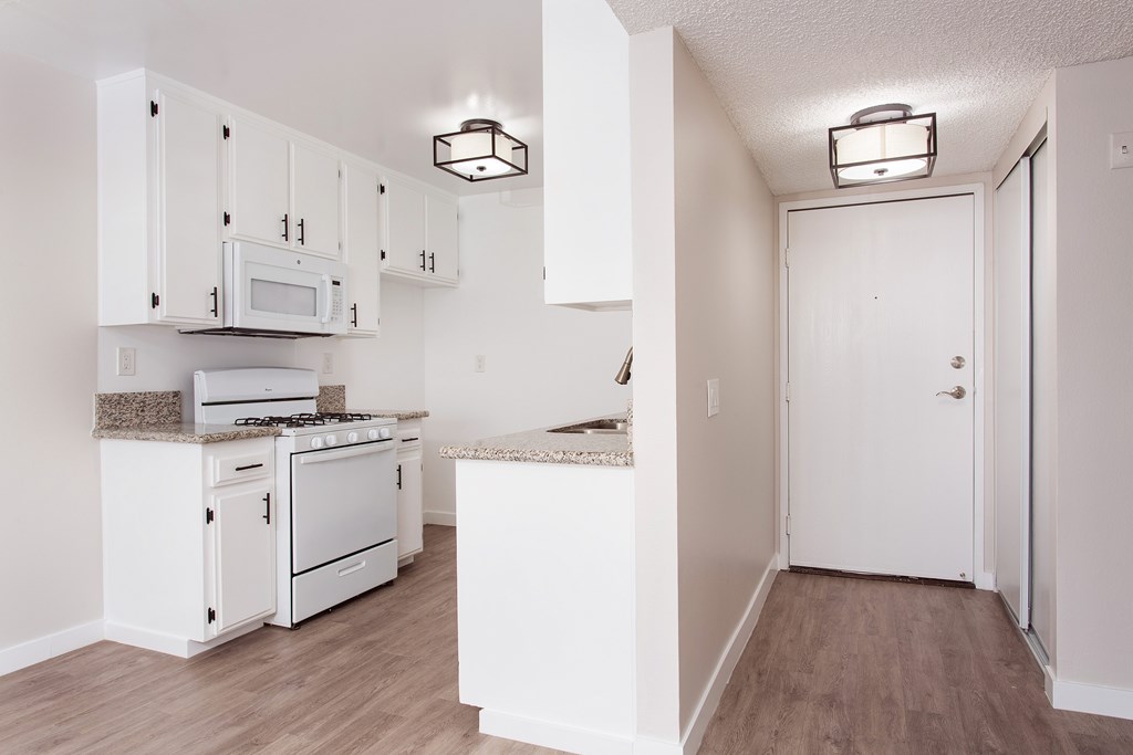 A kitchen with white cabinets and appliances.