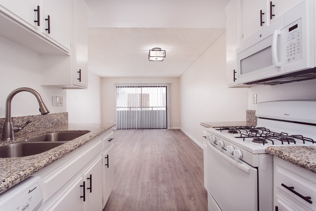 A kitchen with white cabinets and a granite countertop.